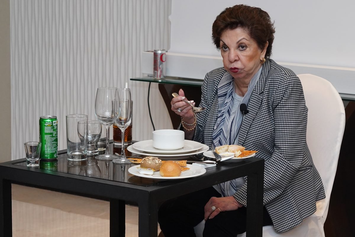 Sabira Merchant holding a knife and fork while speaking