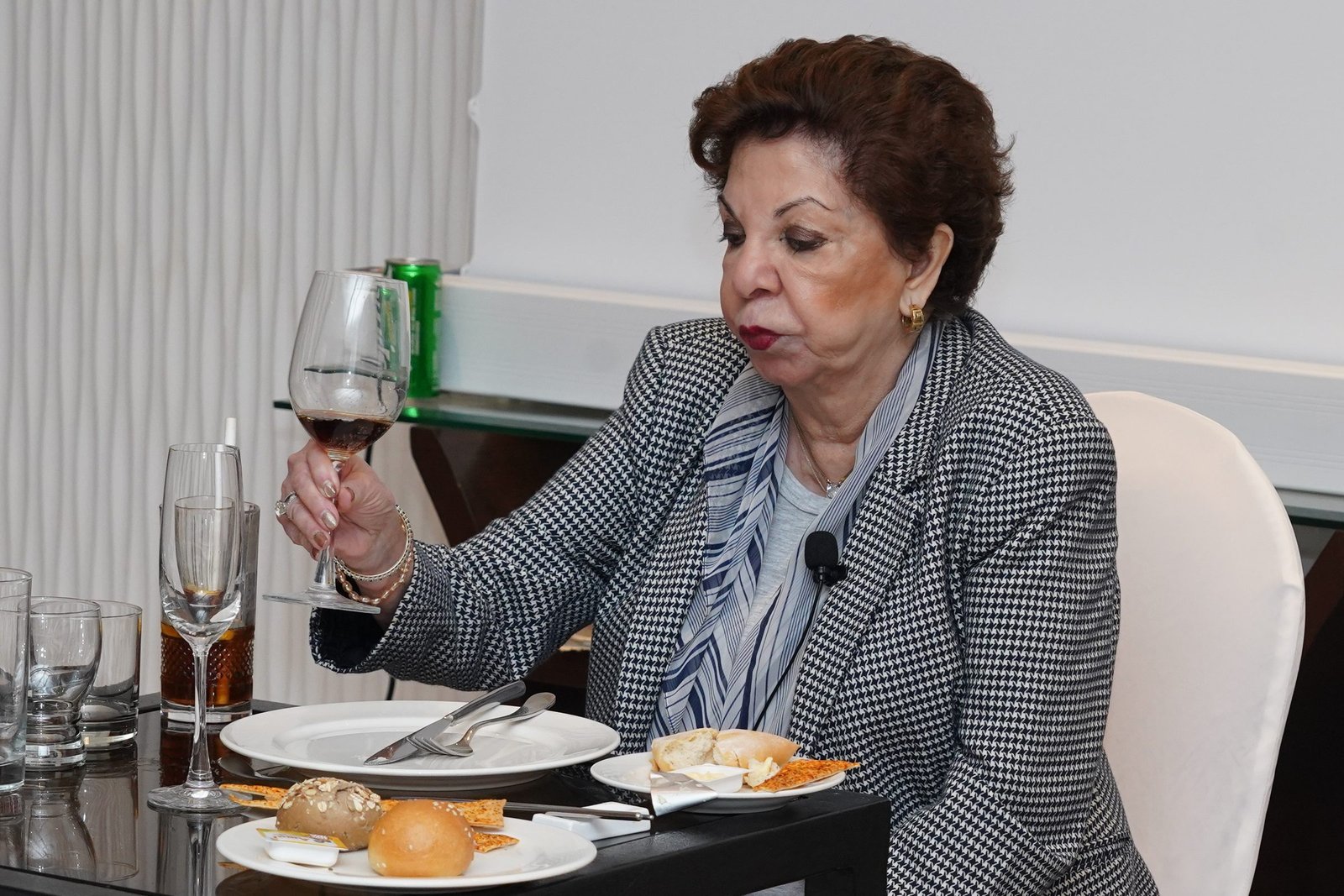 Sabira Merchant holding a wine glass at a laid table during a dining demonstration