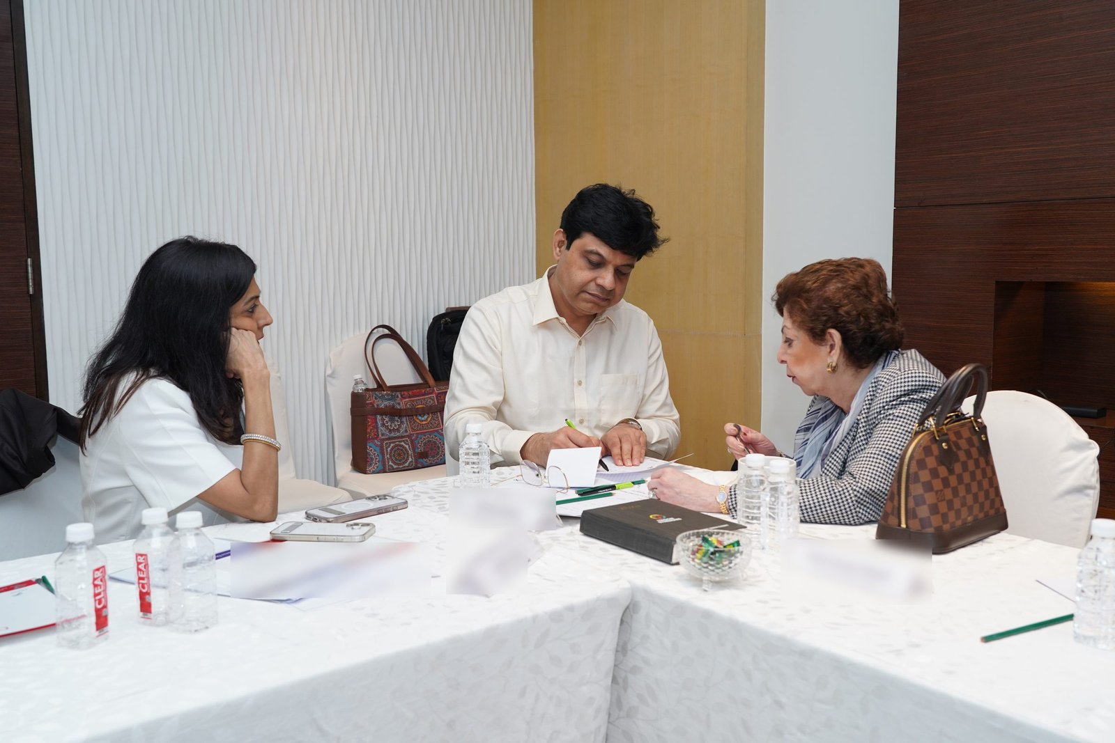 Sabira Merchant and the two directors of Princeton Academy at a table with papers and certificates