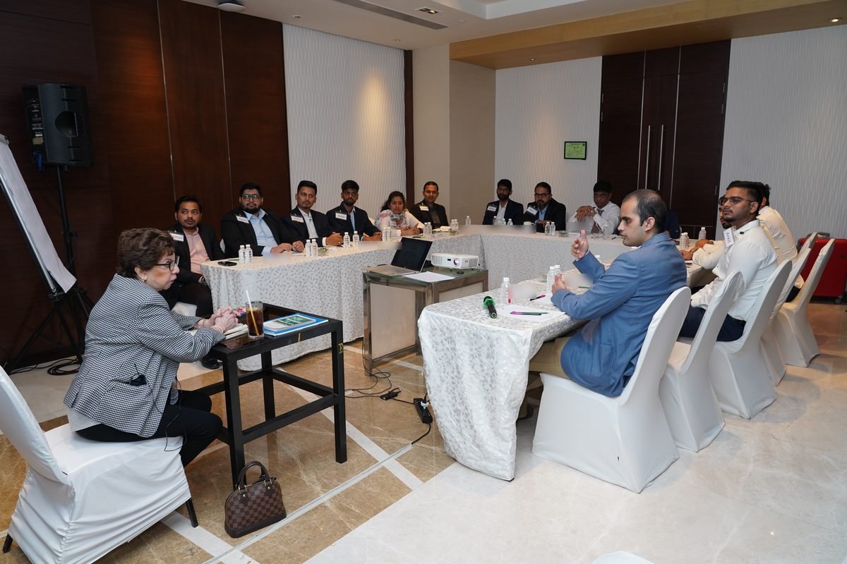 Sabira Merchant seated at the side of the room watching participants during a session