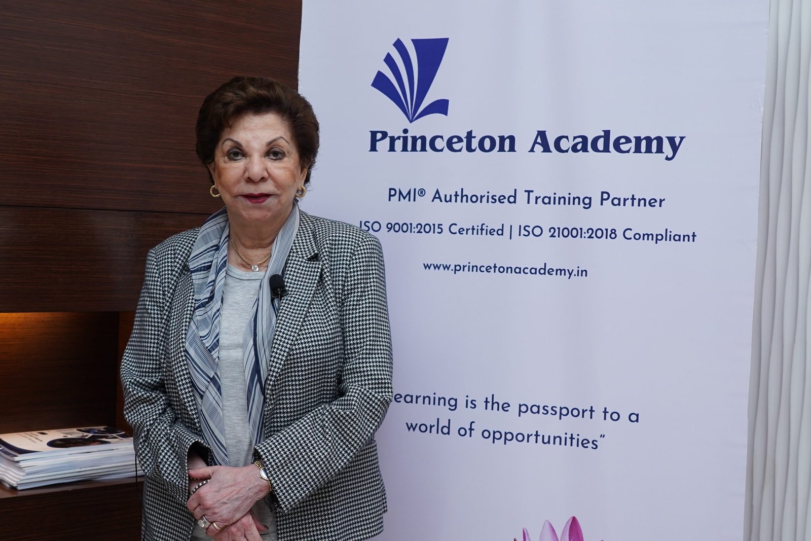 Sabira Merchant standing beside a Princeton Academy banner