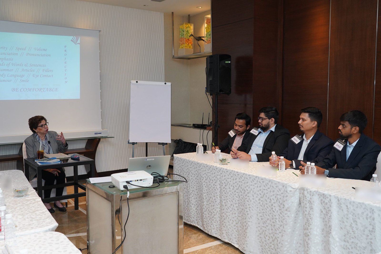 Sabira Merchant teaching a session on projection, with participants seated at a table beside her